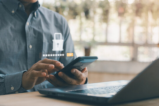 Businessman using smartphone and laptop computer with virtual password input and login button. Concept of secure mobile authentication, user access control and cyber security protection.