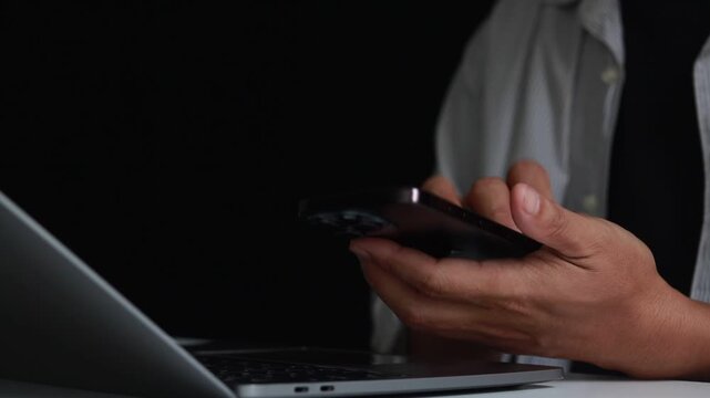 Man using mobile phone and laptop for online authentication at home, male hands typing a password on laptop keyboard for two factor authentication, ensuring data security and online privacy.