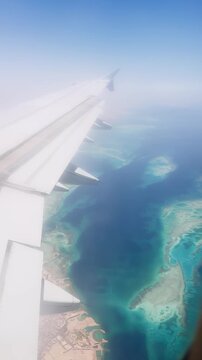 Aerial view of turquoise islands and clear blue sea from airplane window