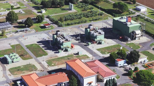 Aerial view of the Snam Rete Gas natural gas compression station with industrial buildings and pipelines surrounded by green landscape in Gallese, Lazio, Italy.
