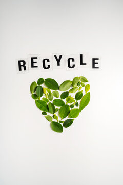 Recycle message with heart shape made of green leaves on white background, sustainability concept
