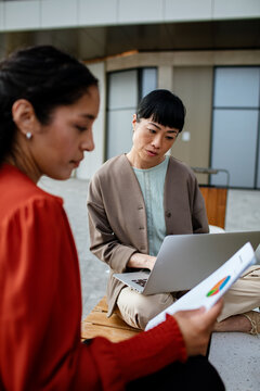 Two businesswomen reviewing charts on laptop outdoors