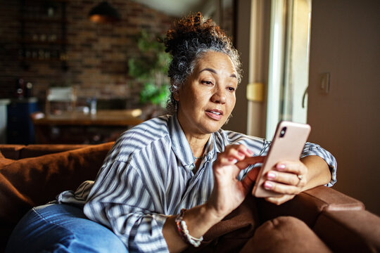 Senior woman using smartphone on sofa at home