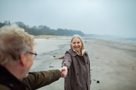 Senior couple holding hands on a cloudy winter beach