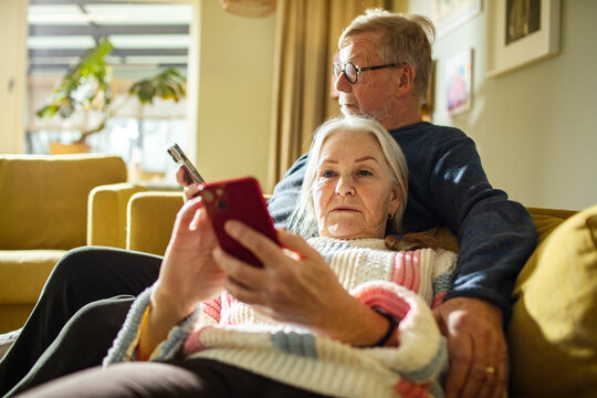 Senior couple relaxing at home using smartphones