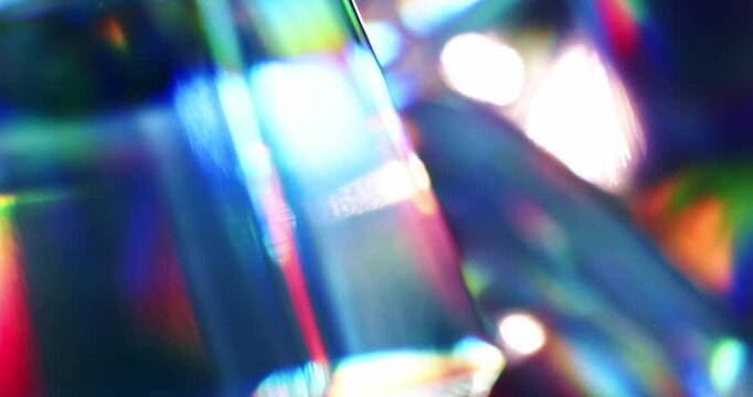 Light reflecting glass in brilliant saturated colors. Radiant lighting through a prism cube creating a visual of a colorful rainbow effect of light refraction. Spinning geometric abstract background.