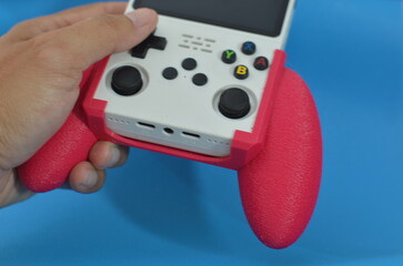 Person holding retro handheld game console with pink 3D printed grip © ahmadiliandy