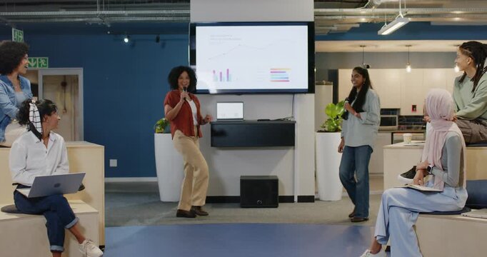 Diverse female team entering from sides at office center presenting on screen with mics for pitch