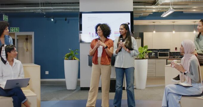 African American and Indian women starting talk presenting charts with mics informing team at work