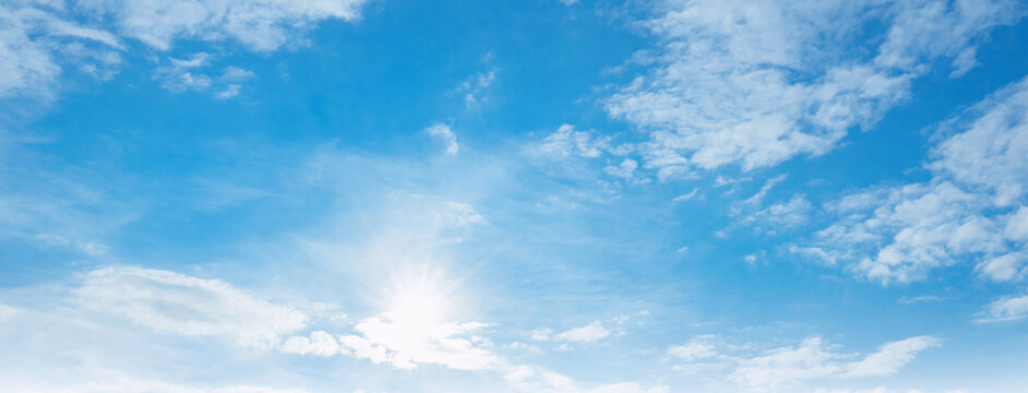 Clear blue sky with soft white clouds