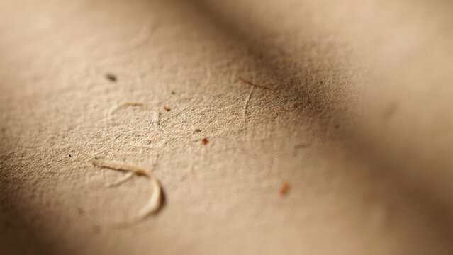 Macro closeup of textured beige handmade paper surface with natural fibers and organic imperfections