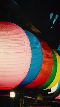 cinematic vertical close-up panning shot of glowing colorful traditional Japanese paper lanterns at night