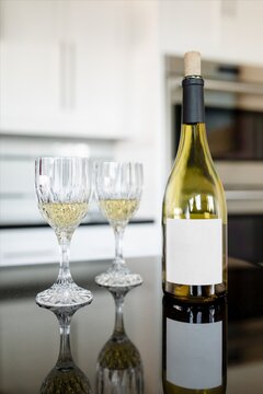 Elegant wine bottle and glasses on reflective kitchen counter