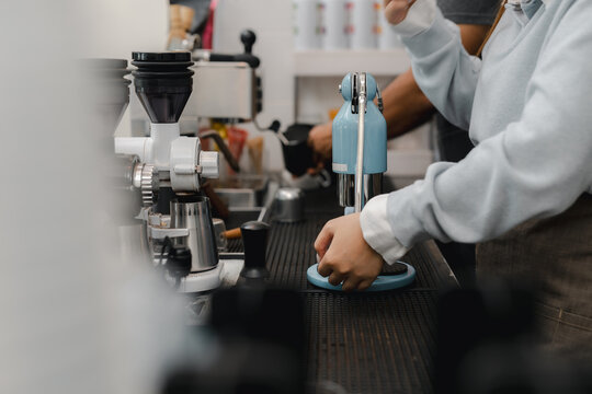 Barista extracting fresh espresso with rich crema using manual coffee press in cafe, showing professional specialty brewing, precision, and handcrafted beverage preparation.