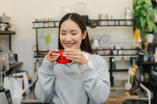 Matcha latte lifestyle concept. Smiling young woman holding fresh green tea latte with creamy foam in cafe, enjoying relaxing drink. matcha, latte, women, cafe, tea.