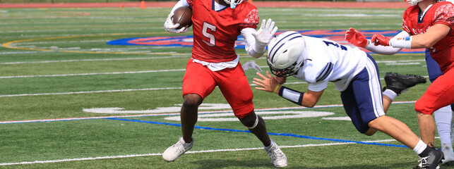 Fototapeta premium Football Player Dodges Tackle During Game on the Field