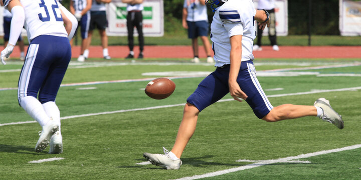 Football Punter Kicks a Ball on the Field During a Game