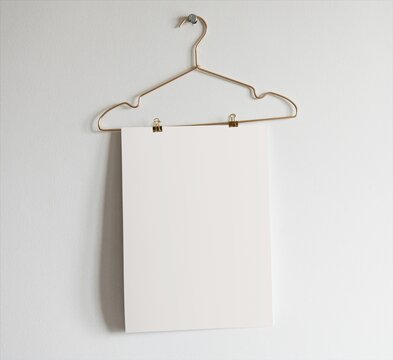 Minimal blank paper clipped on wire hanger mockup on wall