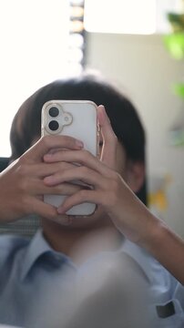 自宅で勉強に集中せずスマホを触るサボる学生、学習中にスマートフォンに触れる学生、ドーパミン中毒注意　顔無しのイメージ縦動画