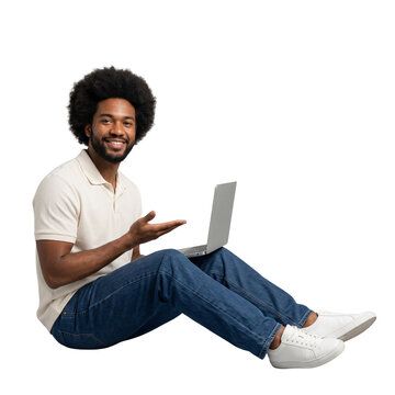 Smiling young man with afro hairstyle sitting on floor holding laptop casual clothes white