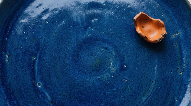 Single broken eggshell piece resting on a textured dark blue ceramic plate