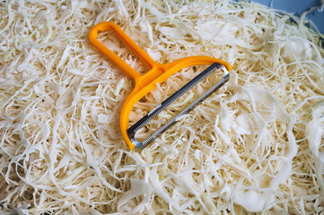 Close-up of a vegetable salad with chopped cabbage and carrots. Yellow shredding tool, shredder. Homemade sauerkraut. Healthy vegetable food concept. © shchus