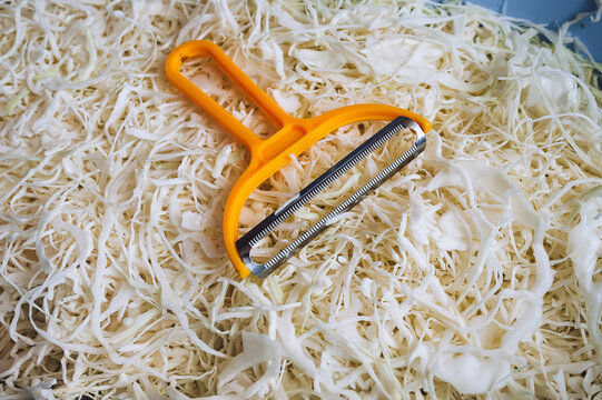 Close-up of a vegetable salad with chopped cabbage and carrots. Yellow shredding tool, shredder. Homemade sauerkraut. Healthy vegetable food concept.