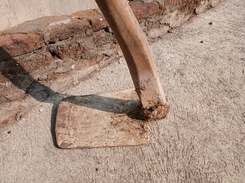 Traditional Gardening Hoe Tool with Wooden Handle on Concrete Ground