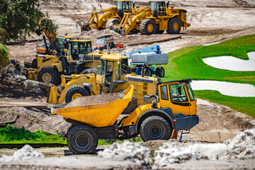 Site dumper hauling earth alongside heavy wheel loaders fleet during golf course construction in USA © Andrei Liashchou