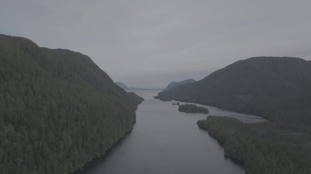 Aerial view of forested islands in a calm coastal fjord on the British Columbia coast &mdash; low pass above still water