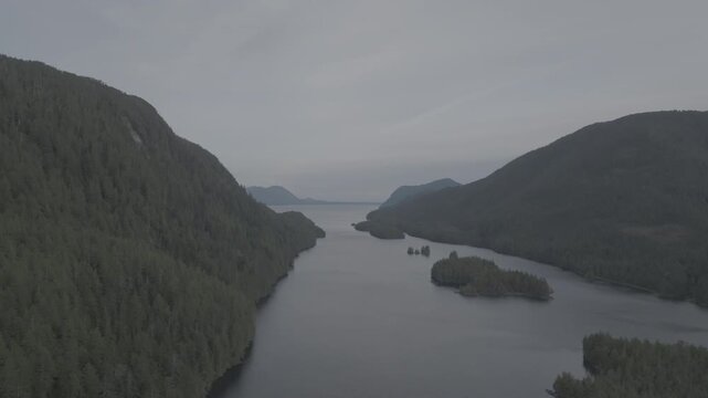 Aerial view of forested islands in a calm coastal fjord on the British Columbia coast &mdash; drifting past a forested point