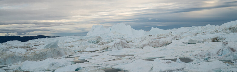 Global Warming and Climate Change - Icebergs and ice from melting glacier in icefjord in Ilulissat, Greenland. Aerial photo of arctic nature ice landscape. Unesco World Heritage Site. Panoramic banner © Maridav