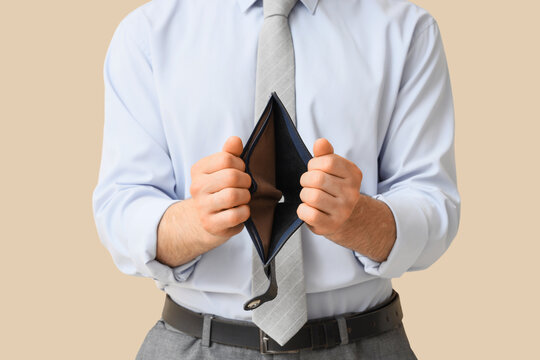 Financial crisis and poverty businessman holding an empty wallet economic hardship inflation and personal debt on a beige background