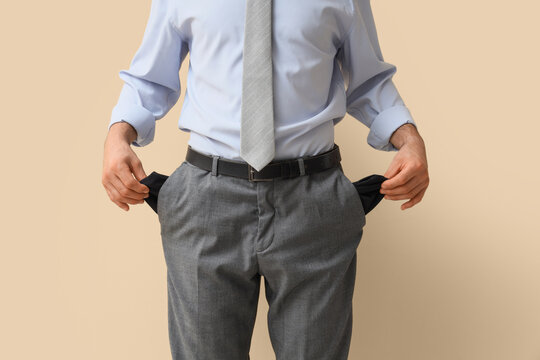 Financial crisis and bankruptcy, businessman showing empty pockets as a sign of poverty and economic hardship in a corporate office environment