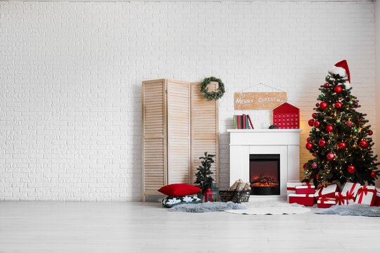 Christmas holiday celebration and home interior design, decorated tree with gifts and fireplace in a cozy living room with white brick wall background
