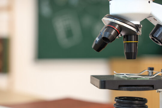 Scientific research and medical discovery, laboratory microscope with glass slide in a classroom or school science lab for education and biology study
