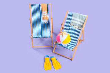 Summer vacation and travel planning, two striped beach chairs with towels and swimming gear on a purple background for holiday leisure © Pixel-Shot