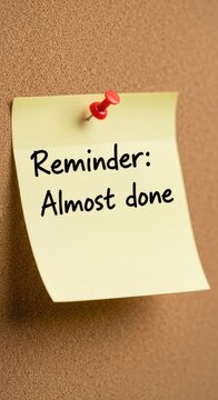 Yellow Sticky Note with Red Pin and Reminder Message on Brown Background.