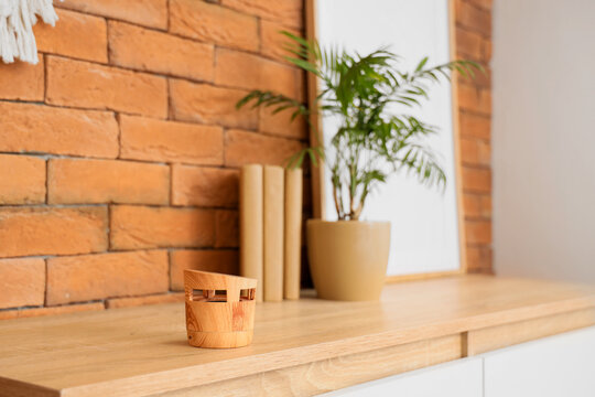 Wireless portable speaker with books and houseplant on commode near brick wall in room