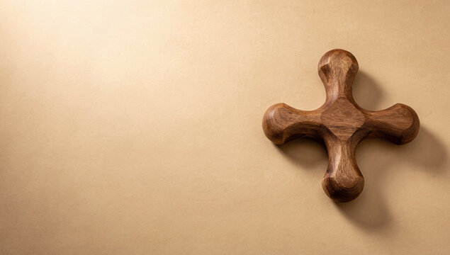 A wooden cross shaped massage tool or spa accessory on a beige background