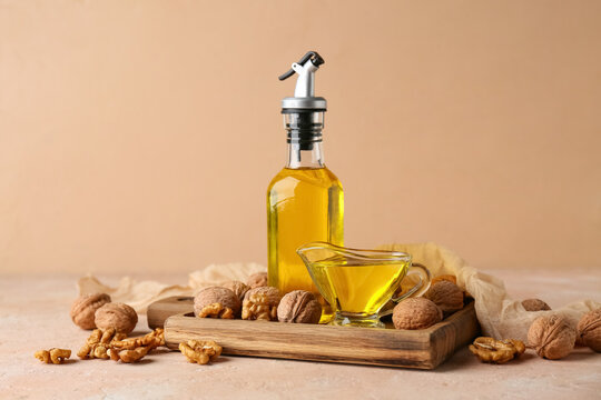 Bottle and gravy boat of fresh walnut oil on beige background