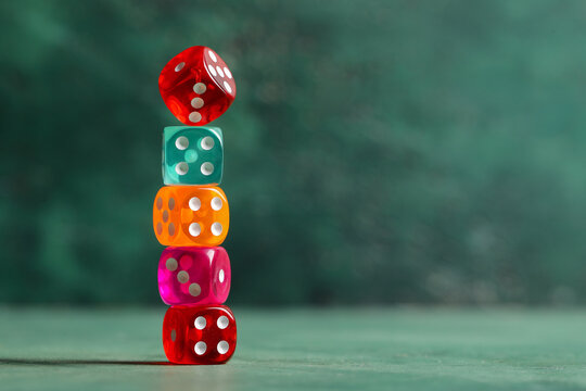Stack of colorful game dices on green background