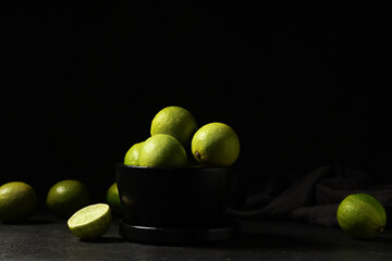 Obraz premium Bowl with fresh ripe limes on black background