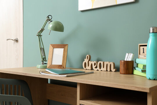 Interior of stylish childrens room with modern workplace near turquoise wall