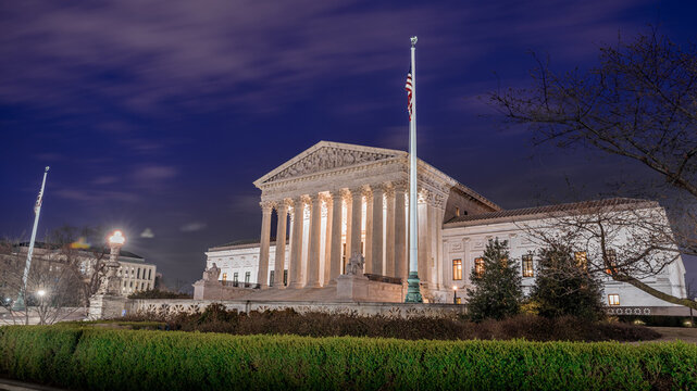 WASHINGTON, DC &mdash; MARCH 18, 2019: The United States Supreme Court Building is illuminated beneath a deep evening sky near the U.S. Capitol.
