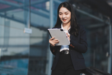 Obraz premium Young businesswoman smiling while working with digital tablet at modern office building