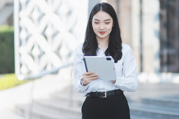 Obraz premium Young professional woman talking on phone and holding coffee outside modern office building