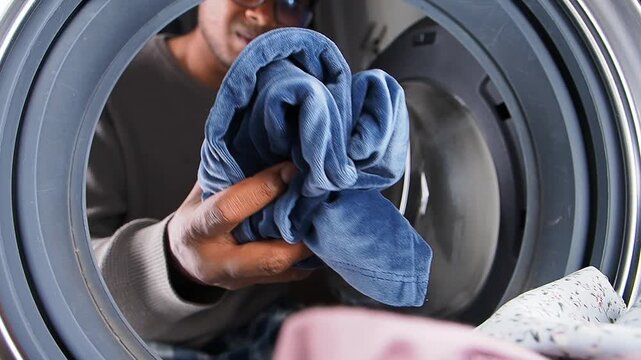 Man removes clothes from washing machine at home in the afternoon