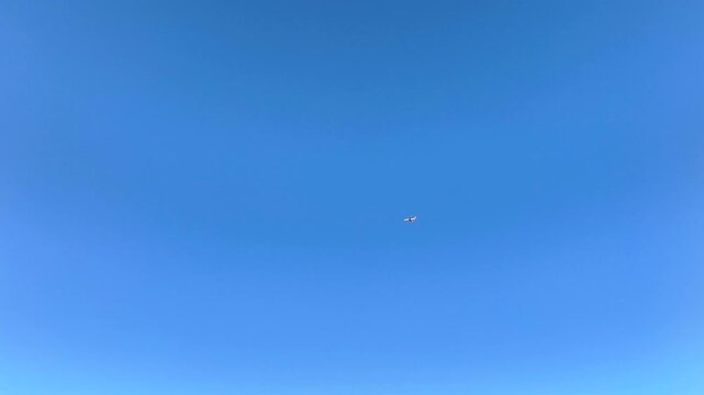 Cinematic 4K shot of a large passenger airplane flying through the blue sky