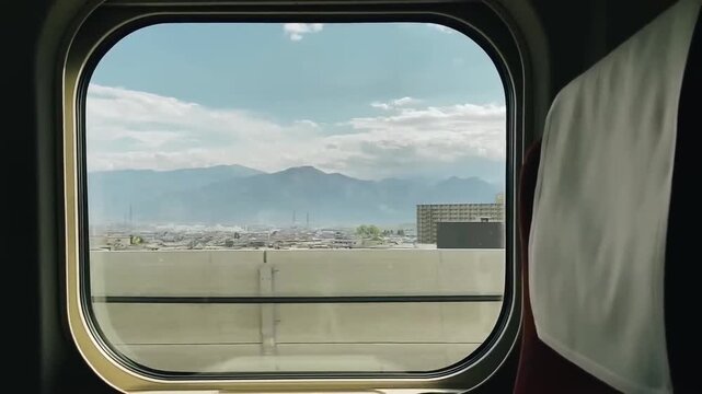 Cinematic interior view from inside a moving passenger train, looking out through the window as the train travels at high speed. The passing landscape is captured with natural motion blur, showing cou